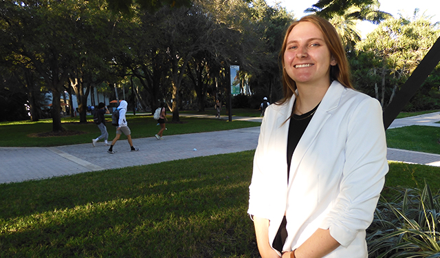 Image of LAS student Jae Lynn Huckaba in a white blazer overlooking the UM campus, smiling into the camera. 